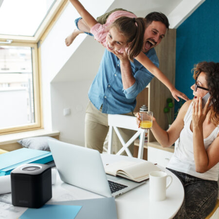 Happy family in living room. Mother works from home ,while her husband and daughter support her .